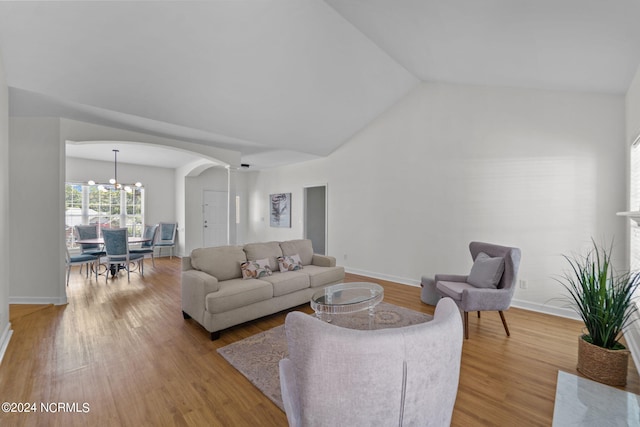 living room featuring lofted ceiling, a notable chandelier, and light wood-type flooring