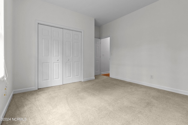 unfurnished bedroom featuring light colored carpet and a closet