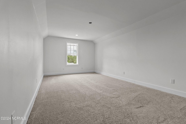 carpeted empty room featuring lofted ceiling