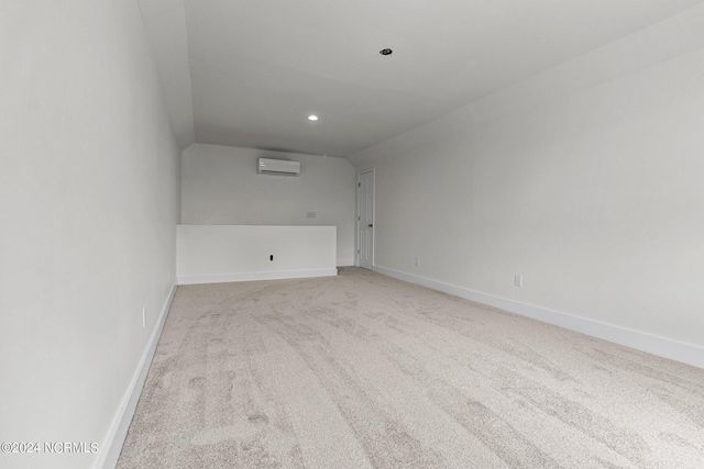 spare room featuring lofted ceiling, light carpet, and an AC wall unit