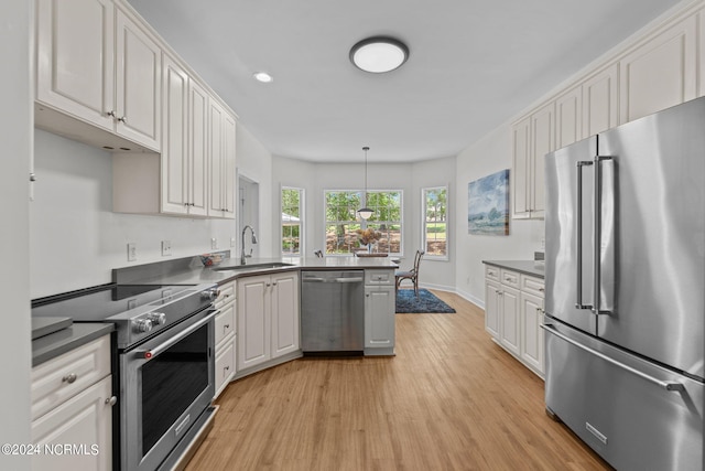 kitchen featuring sink, light wood-type flooring, appliances with stainless steel finishes, pendant lighting, and white cabinets