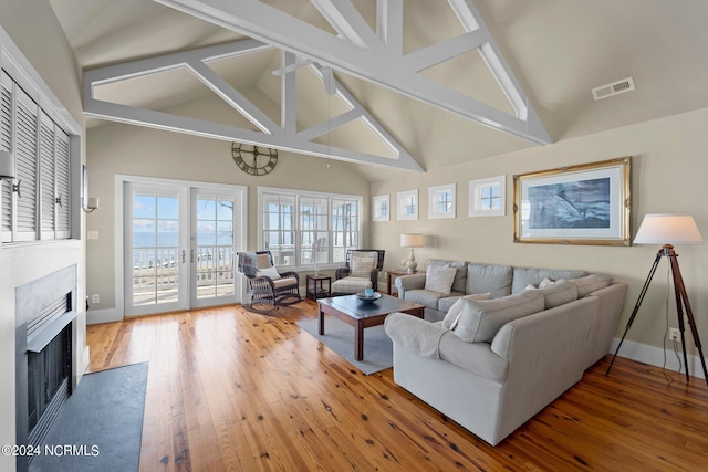 living room featuring hardwood / wood-style floors, beam ceiling, and high vaulted ceiling