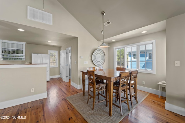 dining room with hardwood / wood-style floors and high vaulted ceiling