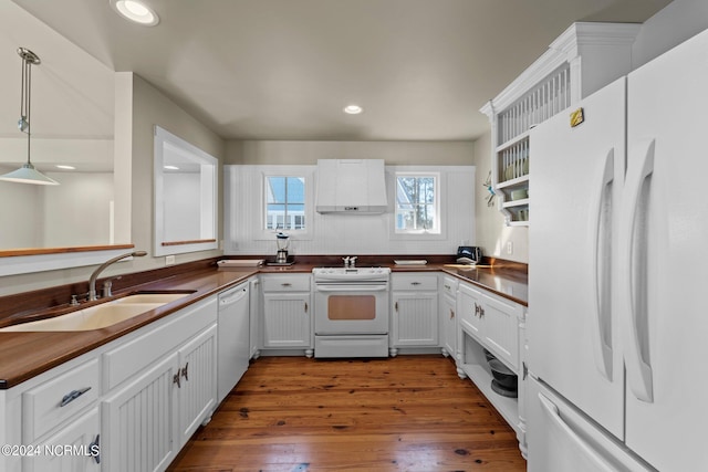 kitchen featuring white appliances, white cabinets, sink, hanging light fixtures, and dark hardwood / wood-style flooring