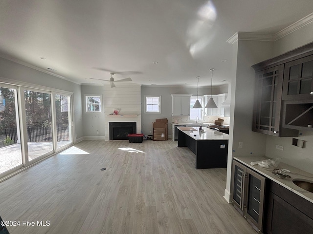 kitchen featuring pendant lighting, a fireplace, an island with sink, and a healthy amount of sunlight