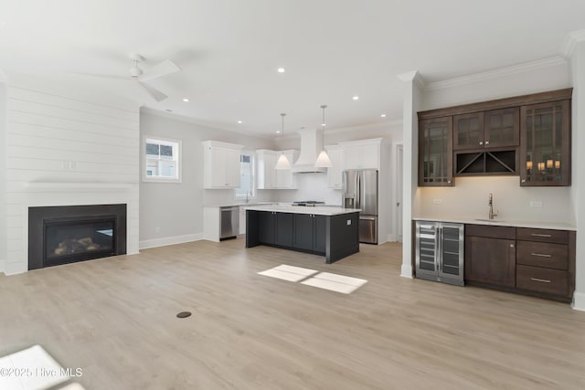 kitchen featuring stainless steel appliances, wine cooler, white cabinets, decorative light fixtures, and custom exhaust hood