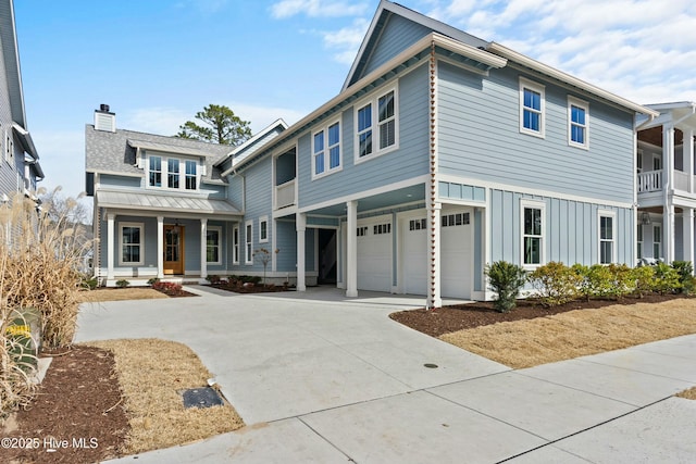 view of front of home featuring an attached garage, covered porch, concrete driveway, board and batten siding, and a chimney