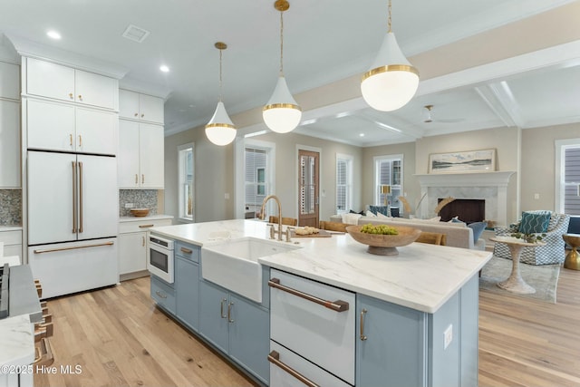 kitchen with visible vents, light wood-style floors, white cabinets, a sink, and white built in refrigerator