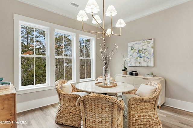 dining area featuring light wood-style flooring, visible vents, baseboards, ornamental molding, and an inviting chandelier