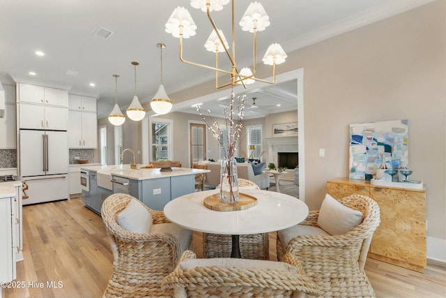 dining room featuring light wood finished floors, recessed lighting, a notable chandelier, and a high end fireplace