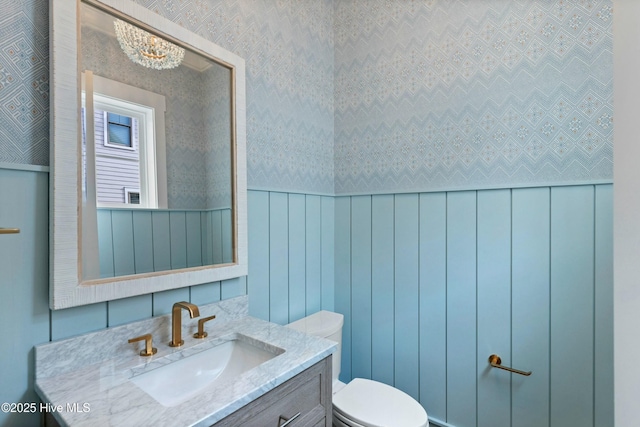 bathroom featuring vanity, toilet, and wallpapered walls