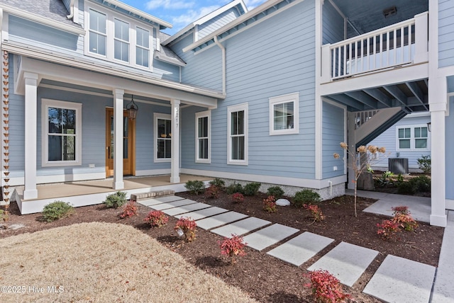 view of exterior entry featuring covered porch and central AC unit