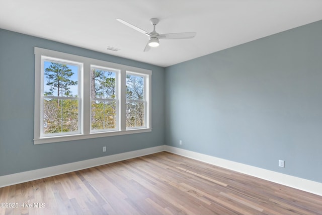 unfurnished room with a ceiling fan, baseboards, visible vents, and wood finished floors