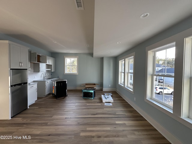 kitchen featuring stainless steel refrigerator, sink, white cabinets, decorative backsplash, and dark wood-type flooring