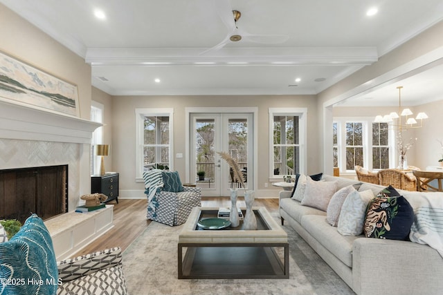 living area with french doors, a premium fireplace, ornamental molding, wood finished floors, and baseboards