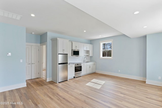 kitchen featuring stainless steel appliances, visible vents, baseboards, white cabinets, and light wood-type flooring