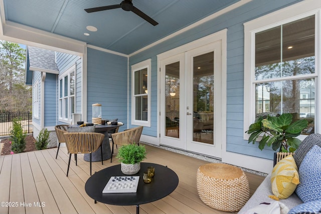 wooden terrace with outdoor dining area, ceiling fan, french doors, and fence