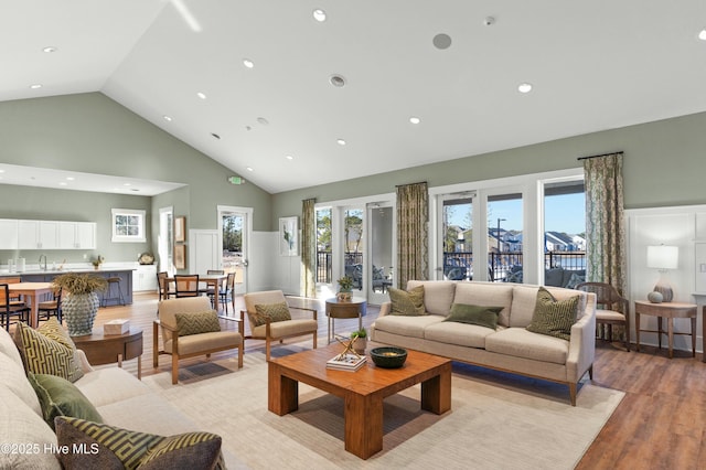 living room featuring high vaulted ceiling, light wood-type flooring, and recessed lighting