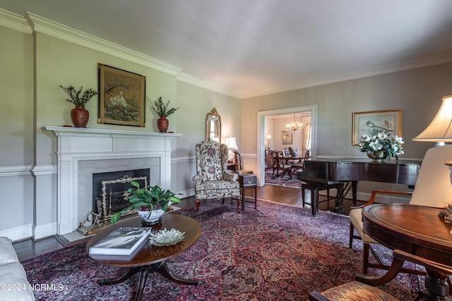 living room with crown molding, wood-type flooring, a fireplace, and a chandelier