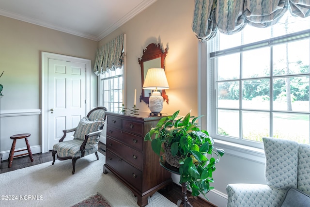 living area featuring hardwood / wood-style flooring, crown molding, and a healthy amount of sunlight