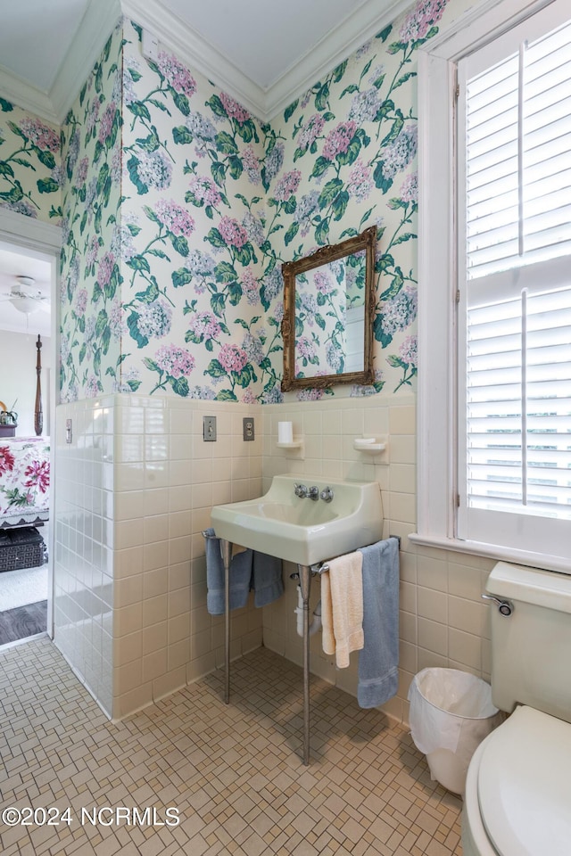 bathroom featuring a healthy amount of sunlight, tile walls, and ornamental molding