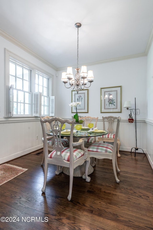 dining area featuring ornamental molding, dark wood-type flooring, and a notable chandelier