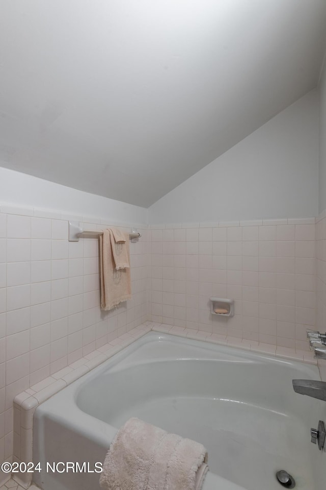 bathroom with vaulted ceiling and a bathing tub