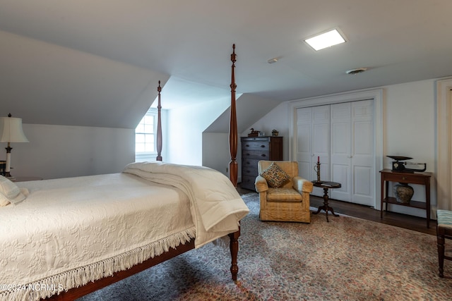 bedroom with a closet, wood-type flooring, and vaulted ceiling