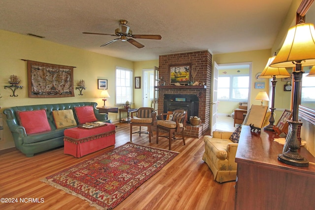 living room featuring plenty of natural light, hardwood / wood-style floors, a textured ceiling, and a brick fireplace