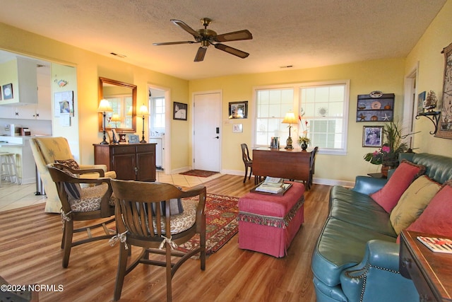 living room with ceiling fan, light hardwood / wood-style floors, and a textured ceiling