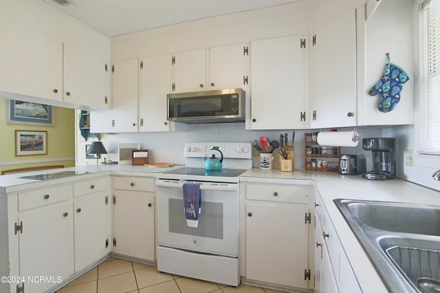 kitchen featuring electric stove, sink, and white cabinets