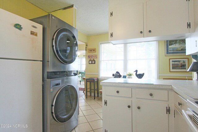 laundry area with stacked washing maching and dryer, a textured ceiling, and light tile patterned floors