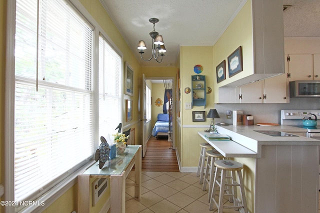 kitchen featuring hanging light fixtures, a kitchen breakfast bar, a healthy amount of sunlight, a textured ceiling, and light tile patterned flooring