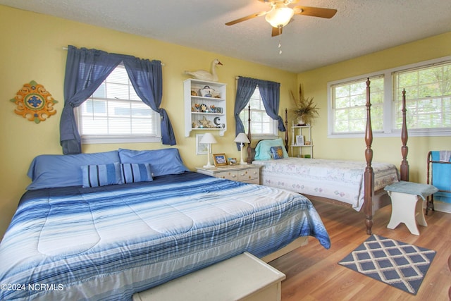 bedroom featuring ceiling fan, hardwood / wood-style floors, and a textured ceiling