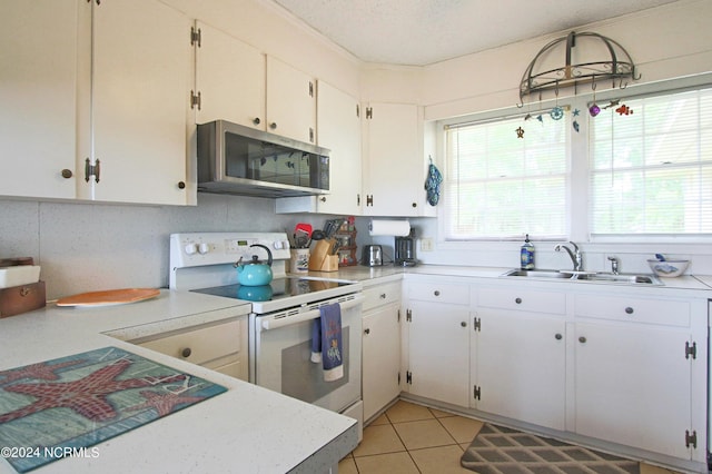 kitchen with sink, a textured ceiling, light tile patterned floors, electric stove, and white cabinets