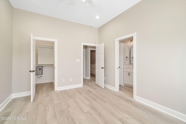 unfurnished bedroom with ceiling fan, ensuite bath, a walk in closet, and light hardwood / wood-style floors