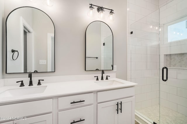 bathroom with a shower with shower door and double vanity