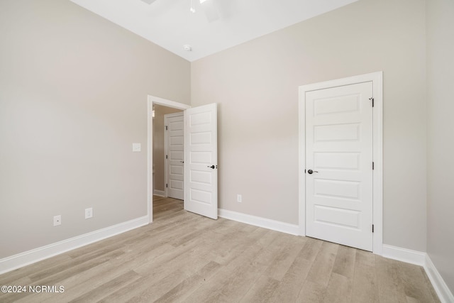 unfurnished bedroom featuring ceiling fan, light wood-type flooring, and a high ceiling