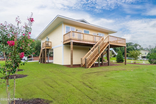 rear view of house with a wooden deck and a yard