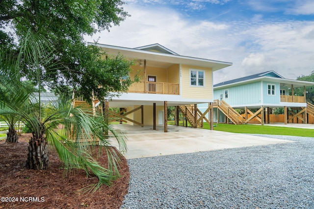 view of front of home with covered porch, driveway, a carport, and stairway