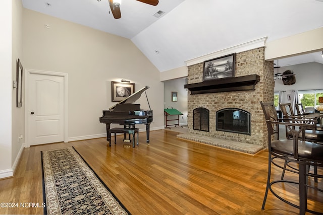 living area featuring a fireplace, wood finished floors, visible vents, baseboards, and a ceiling fan