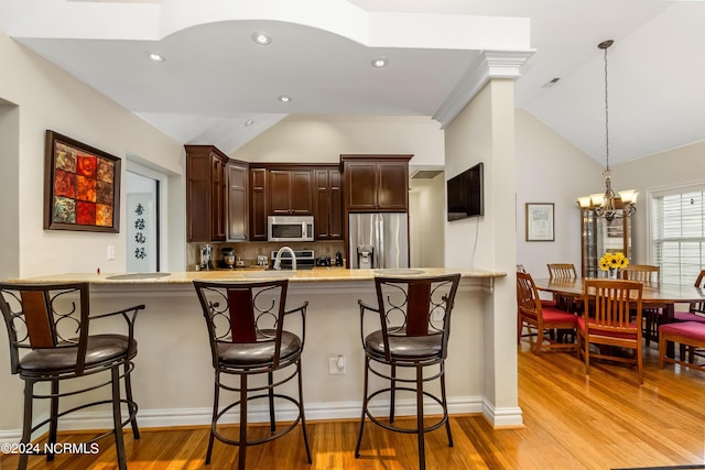 kitchen featuring appliances with stainless steel finishes, lofted ceiling, and a peninsula