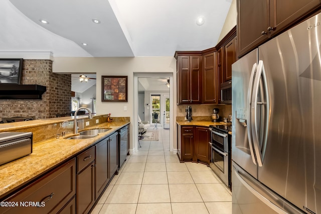 kitchen featuring lofted ceiling, light stone counters, light tile patterned flooring, a sink, and appliances with stainless steel finishes