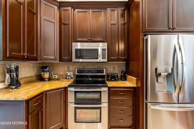 kitchen with tasteful backsplash, light stone counters, and stainless steel appliances