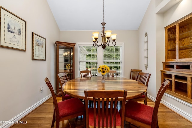 dining room with vaulted ceiling, baseboards, wood finished floors, and an inviting chandelier