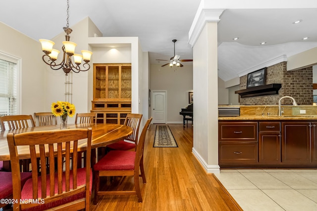 dining area featuring ceiling fan with notable chandelier, high vaulted ceiling, light wood-type flooring, and baseboards