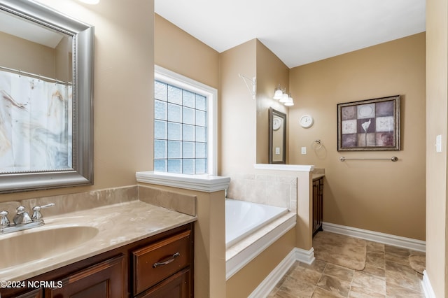 full bathroom featuring vanity, baseboards, and a bath