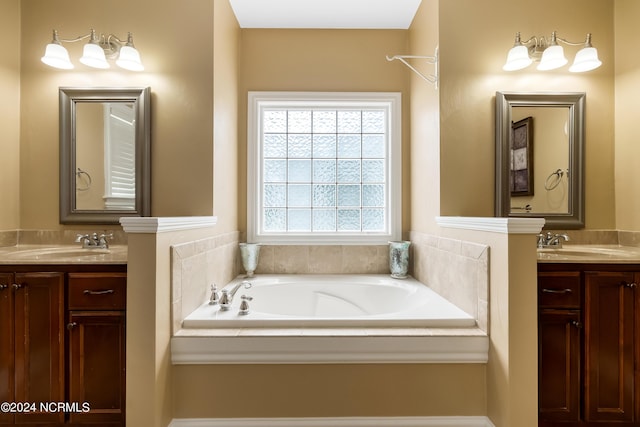 full bath with two vanities, a sink, and a garden tub