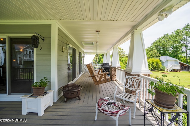 wooden terrace featuring a fire pit and a porch