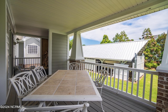 wooden terrace with outdoor dining area and a yard